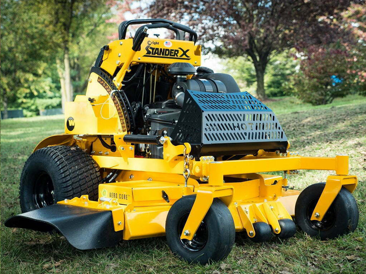 Photo of the COX Mowers Commercial Stander® X Gen2 Mower sitting on a lawn with trees in the background